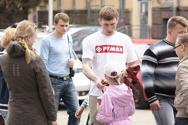 А вот совсем недавнее фото — кто узнает в этом парне, раздающем георгиевские ленточки в Минске, того, что обнимается с Лущем и носит стилизованную футболку с «88» (см. предыдущее фото)?